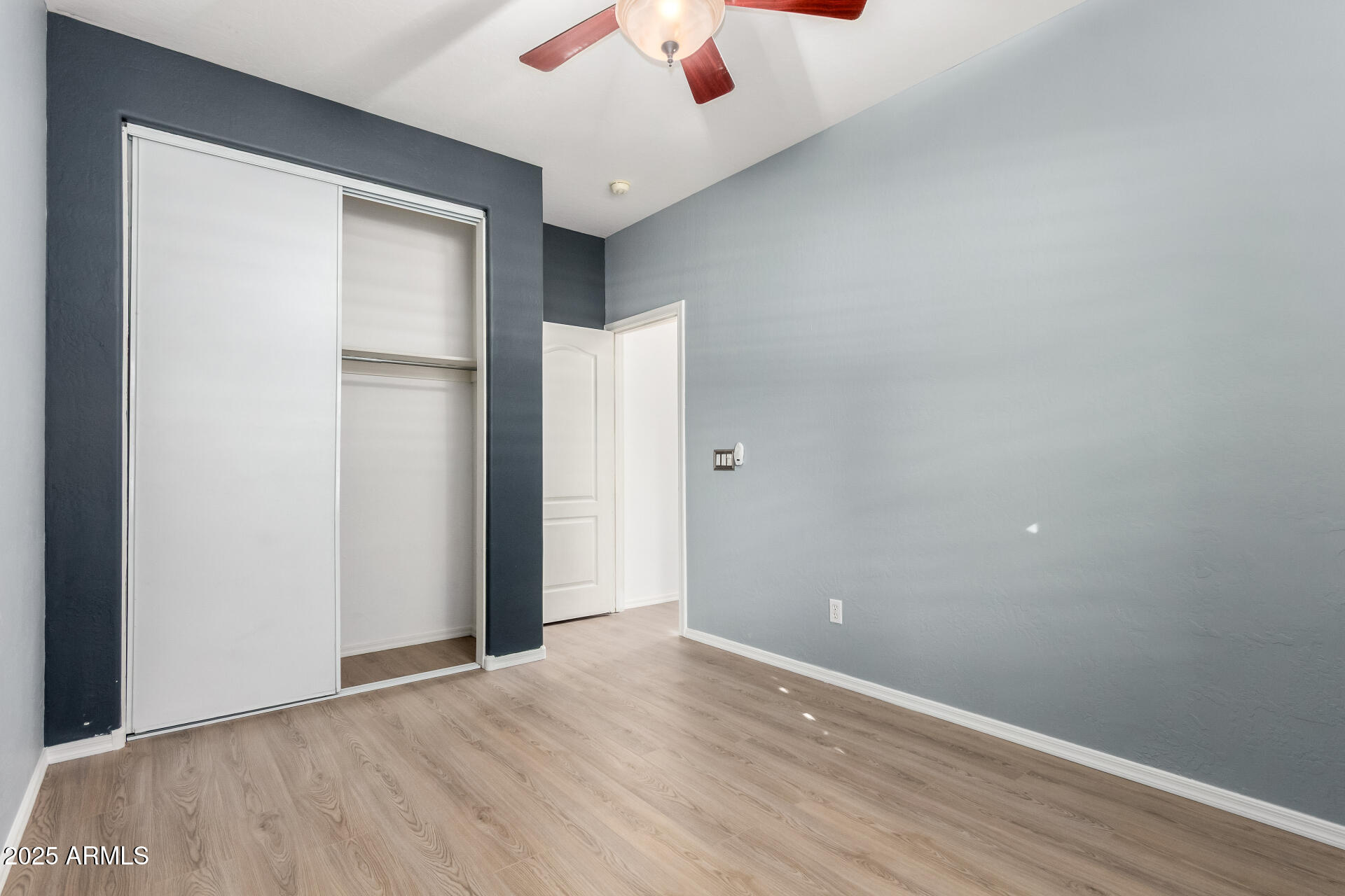1126 East Pedro Road Phoenix, AZ 85042 - Photo 17 of 34 a view of an empty room with wooden floor and a ceiling fan