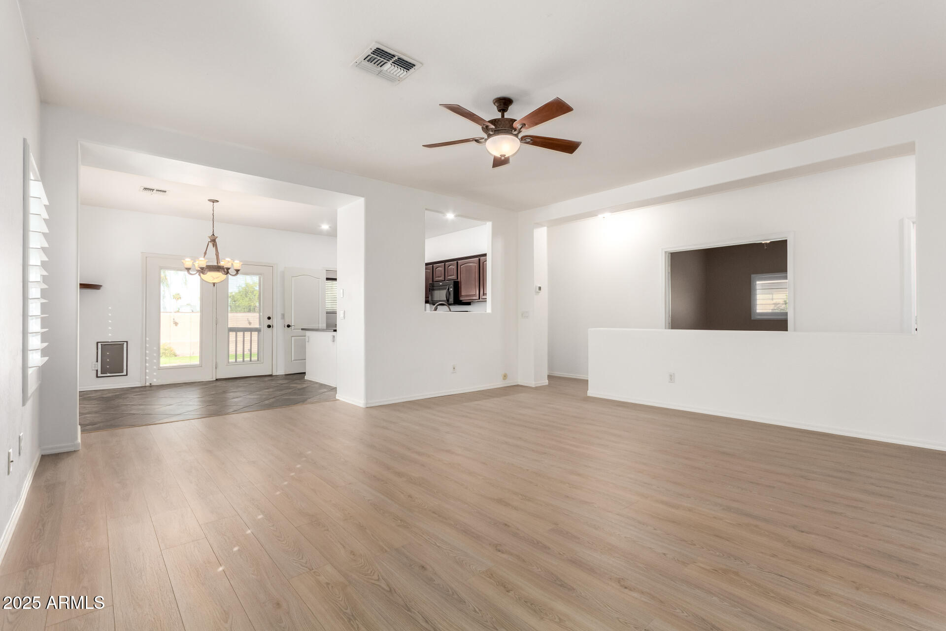1126 East Pedro Road Phoenix, AZ 85042 - Photo 4 of 34 a view of an empty room with wooden floor and a ceiling fan