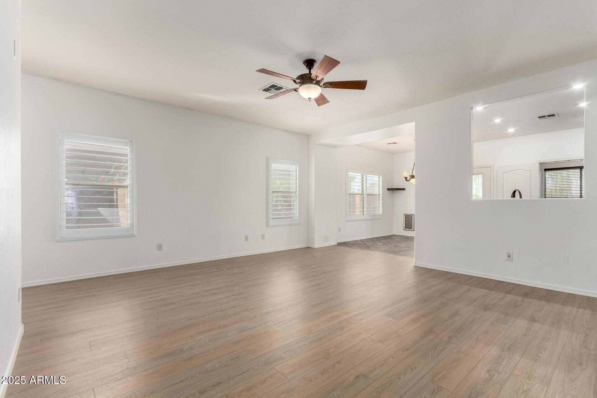 1126 East Pedro Road Phoenix, AZ 85042 - Photo 5 of 34 an empty room with wooden floor a ceiling fan and windows