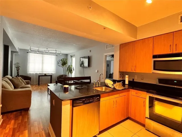 a living room with stainless steel appliances granite countertop a sink and cabinets