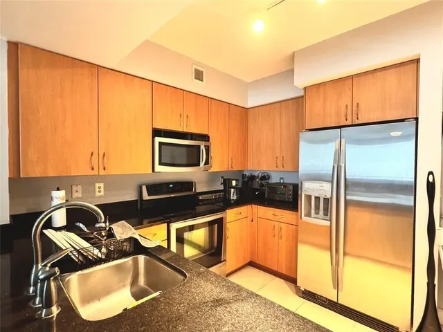 a kitchen with granite countertop a sink a counter top space appliances and cabinets