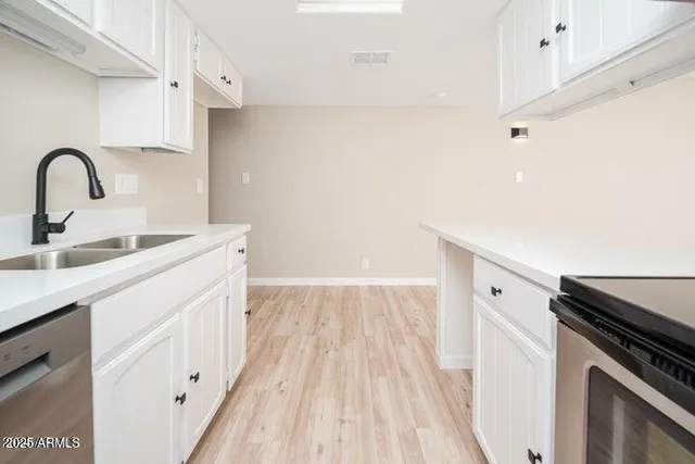 a view of a kitchen with kitchen island a sink wooden floor and stainless steel appliances