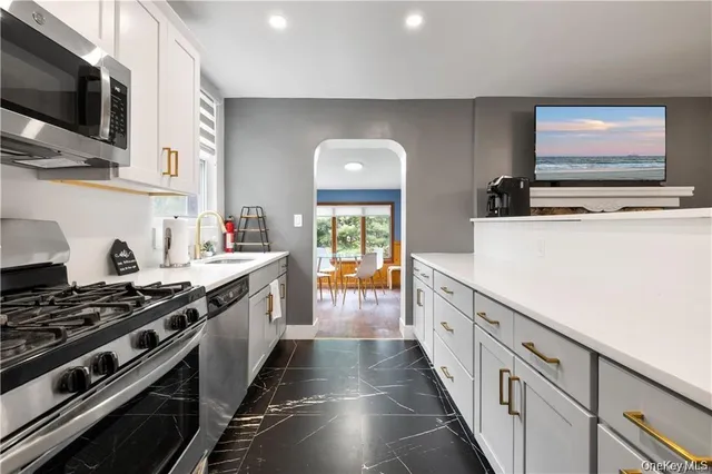 a kitchen with stainless steel appliances a stove top oven a sink a microwave and cabinets