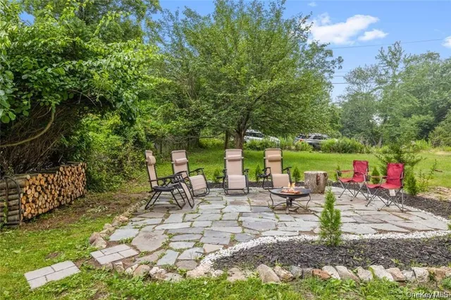 a view of a patio with table and chairs potted plants and large tree