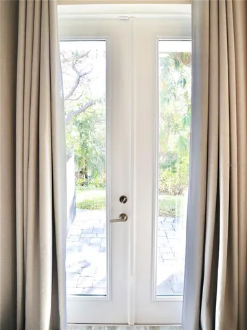 a view of a white house with a large tree and wooden fence