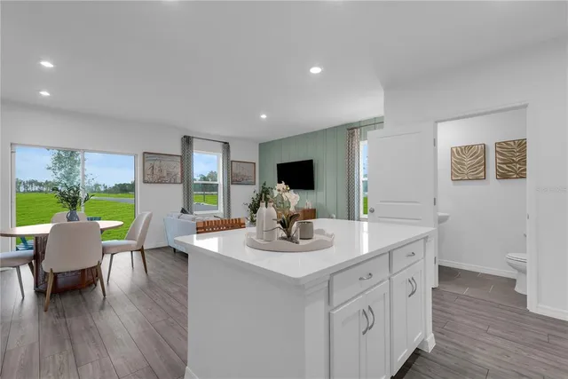 a kitchen with stainless steel appliances granite countertop a refrigerator a stove top oven a sink dishwasher and white cabinets with wooden floor