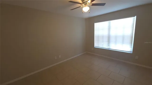 an empty room with a window and a fan