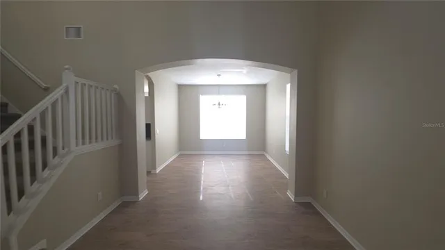 a view of a hallway to a livingroom with wooden floor and door
