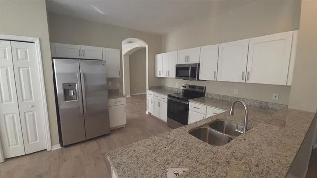 a kitchen with stainless steel appliances granite countertop a refrigerator and a sink