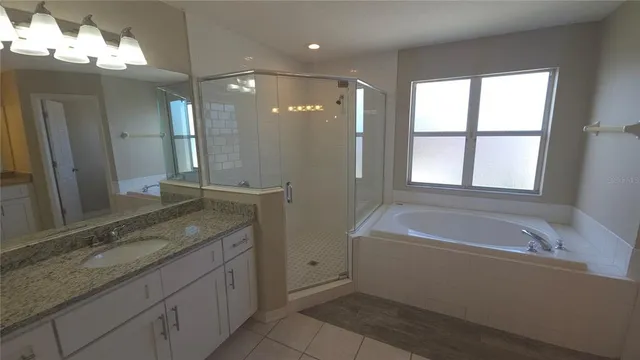 a bathroom with a granite countertop sink a large mirror and a bathtub