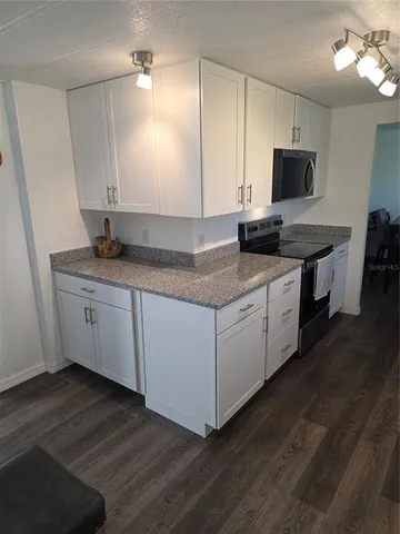 a kitchen with granite countertop a sink cabinets and wooden floor