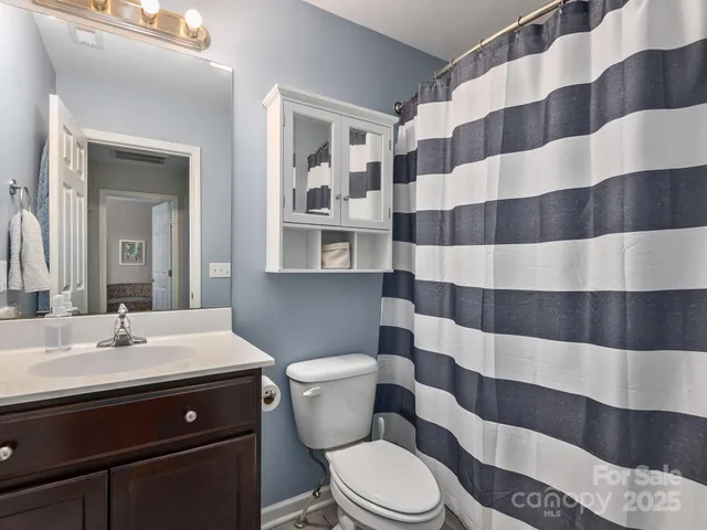 a bathroom with a sink a toilet a mirror and shower curtain