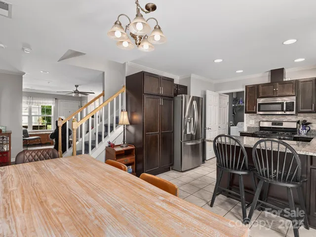 a kitchen with stainless steel appliances kitchen island granite countertop a refrigerator a stove a oven with a dining table and chairs with wooden floor