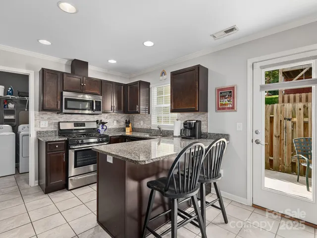 a kitchen with stainless steel appliances granite countertop a stove top oven a sink dishwasher a dining table and chairs