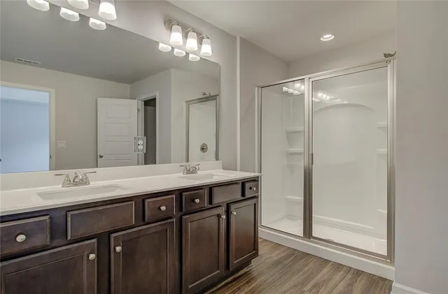 a bathroom with a double vanity sink mirror and shower