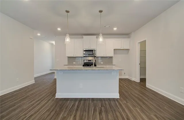 a large kitchen with stainless steel appliances a large counter top a sink a refrigerator and a stove