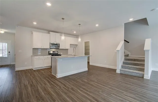a kitchen with wooden floors stainless steel appliances and white cabinets