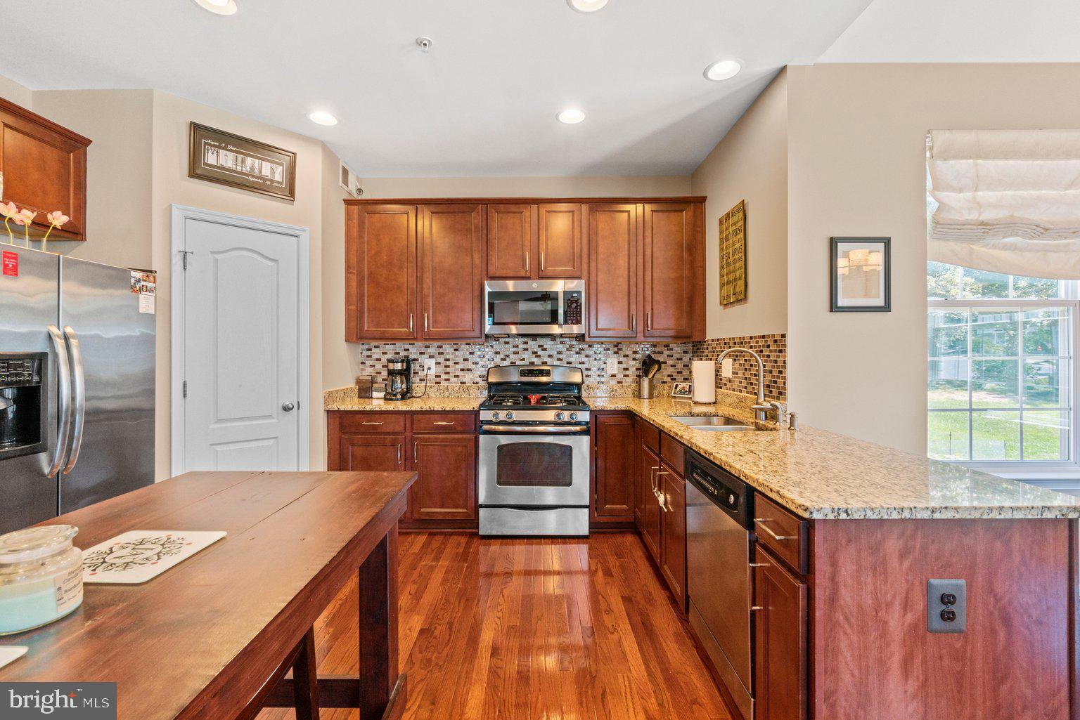 900 McCune Road Middle River, MD 21220 - Photo 16 of 55 a kitchen with stainless steel appliances granite countertop a refrigerator a stove top oven a sink dishwasher and wooden cabinets with wooden floor