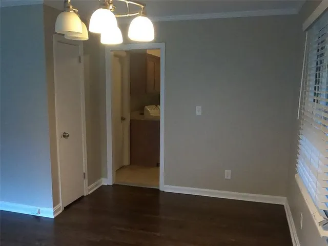 an empty room with wooden floor mirror and windows
