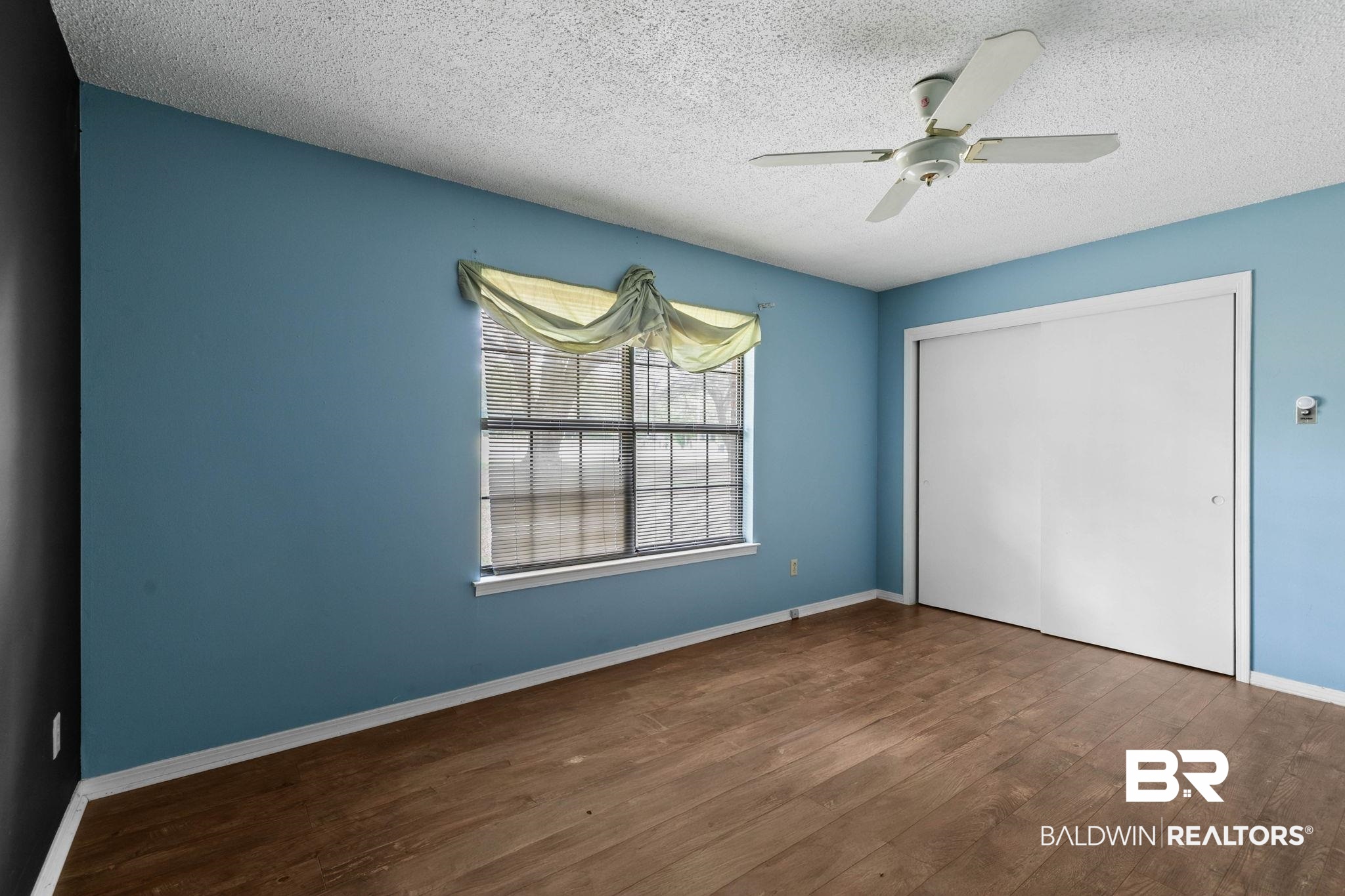 13653 Roberts Road Loxley, AL 36551 - Photo 19 of 33 Interior room featuring wood-finish flooring, a window with blinds, a ceiling fan, and sliding closet doors