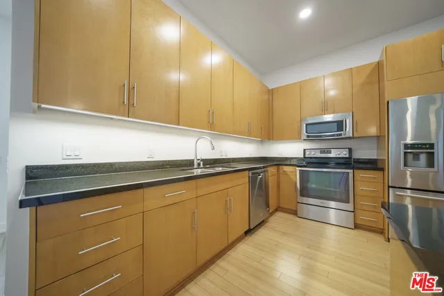 a kitchen with granite countertop cabinets stainless steel appliances and a counter space