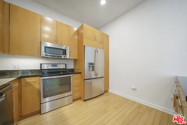 a kitchen with stainless steel appliances granite countertop a refrigerator microwave and sink