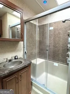 a bathroom with a granite countertop sink a mirror and shower
