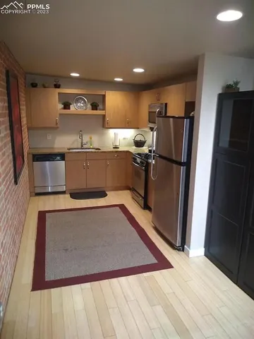 a large kitchen with stainless steel appliances a refrigerator and a counter top space
