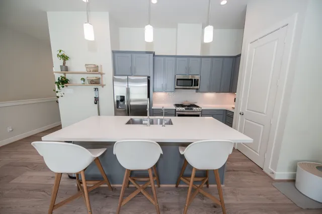 a kitchen with stainless steel appliances a dining table chairs and wooden floor