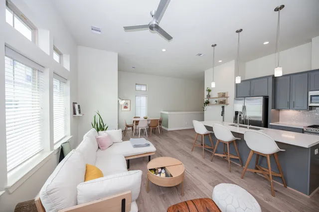 a living room with furniture kitchen view and a large window