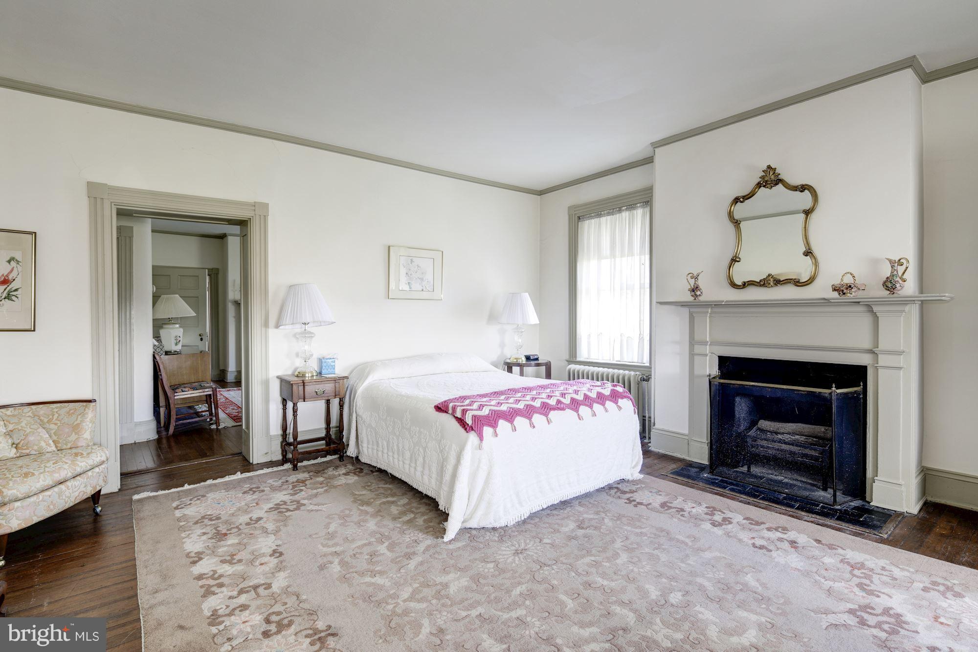 16449 Ed Warfield Road Woodbine, MD 21797 - Photo 38 of 102 a spacious bedroom with a bed and a fireplace