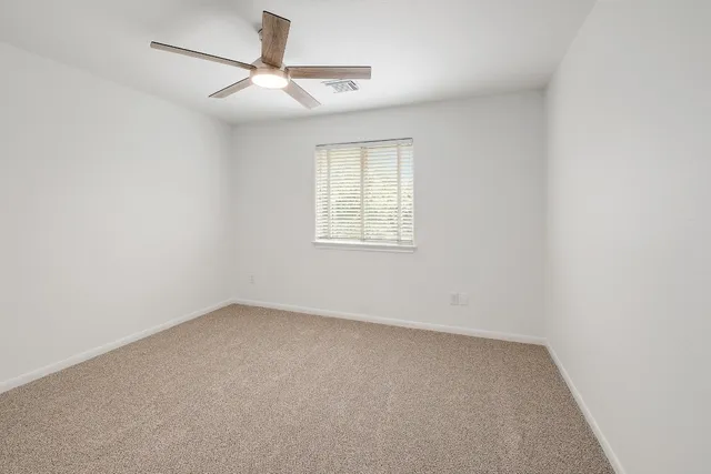 an empty room with a window and ceiling fan