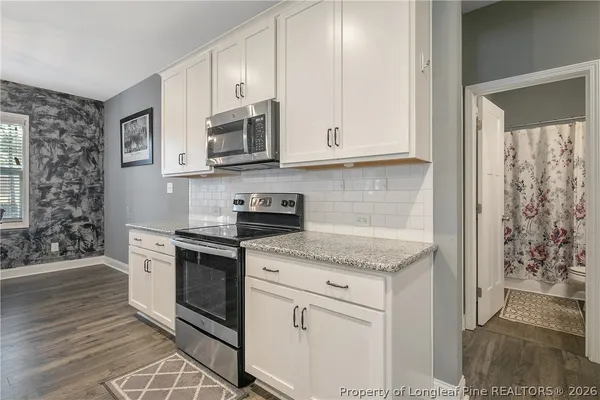 a kitchen with granite countertop stainless steel appliances a sink stove top oven and cabinets
