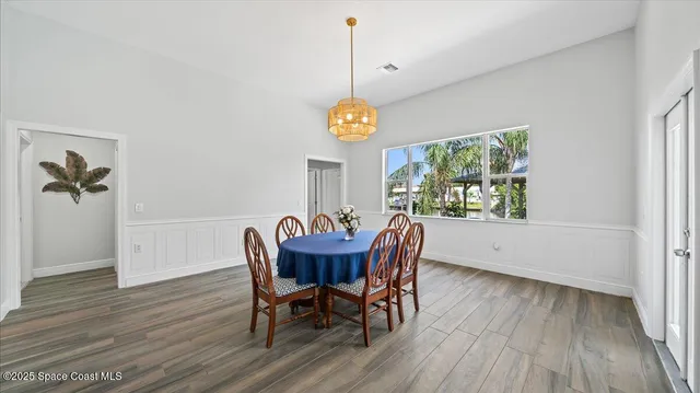 a dining room with furniture a chandelier and wooden floor