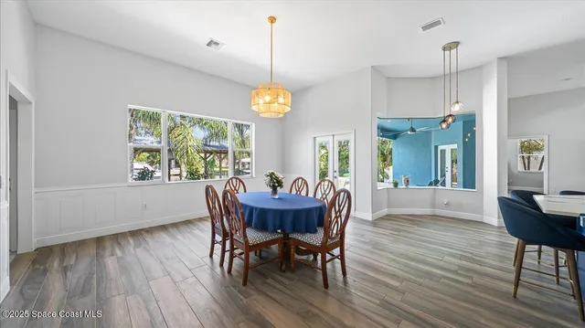 a dining room with wooden floor a chandelier a wooden table and chairs