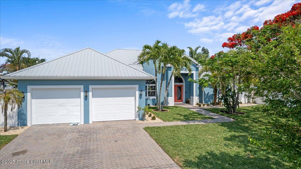 121 Boca Ciega Road Cocoa Beach, FL 32931 - Photo 2 of 50 a front view of a house with a yard and garage