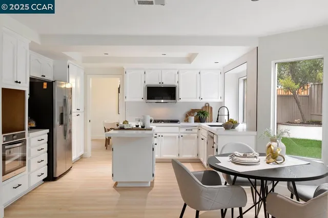 a kitchen with stainless steel appliances granite countertop a stove a sink a microwave a dining table and chairs