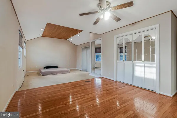 a view of empty room with wooden floor and fan