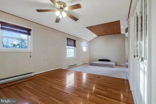 a view of empty room with wooden floor and fan