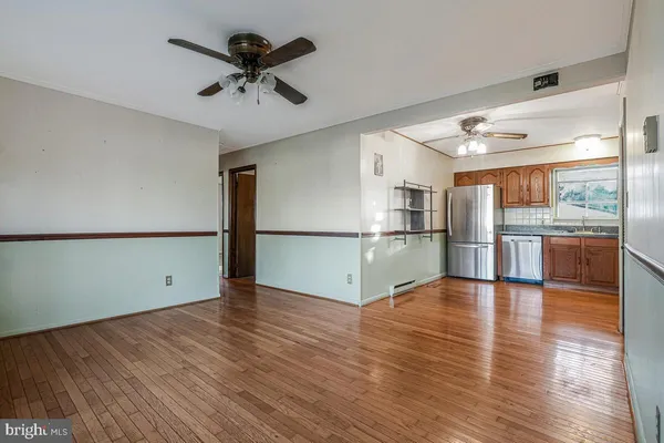 a view of empty room with wooden floor and a kitchen
