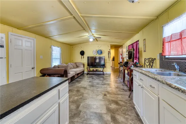 a large living room with stainless steel appliances granite countertop couches a coffee table and chandelier