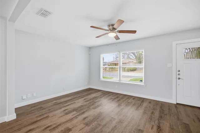 a view of empty room with wooden floor and fan