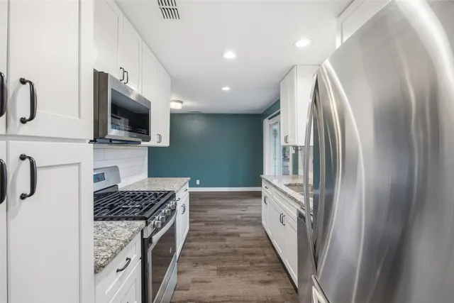 a kitchen with kitchen island granite countertop a stove and a refrigerator