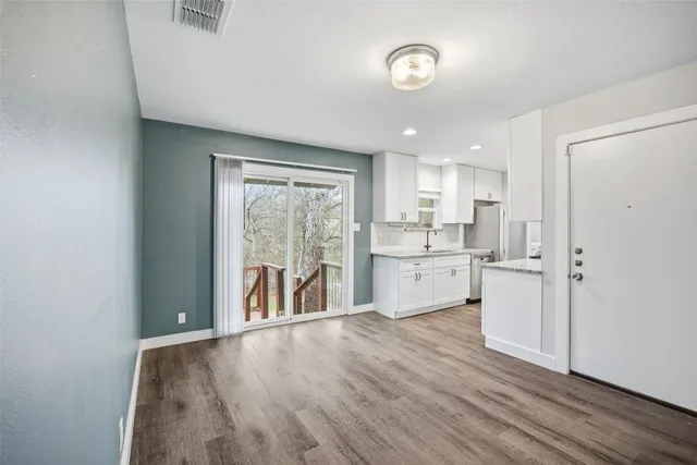 a kitchen with white cabinets and wooden floor