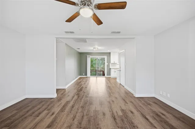 a view of empty room with wooden floor and fan