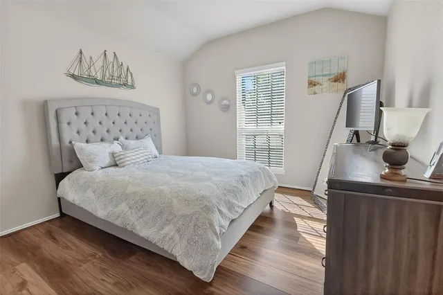 a bedroom with a bed and a flat tv screen on a dresser