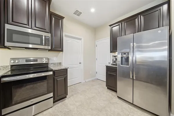 a kitchen with stainless steel appliances kitchen island granite countertop a refrigerator stove and microwave