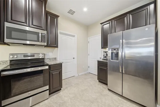 a kitchen with stainless steel appliances kitchen island granite countertop a refrigerator stove and microwave