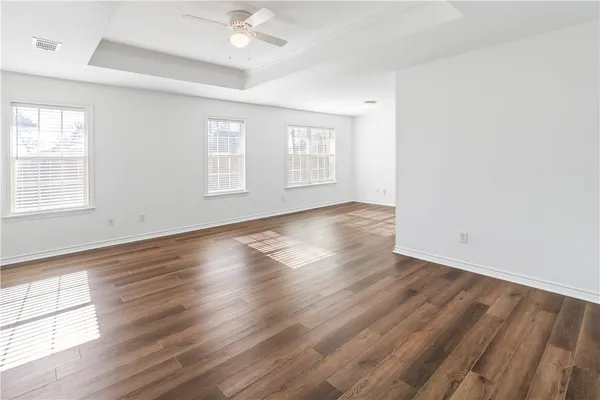 an empty room with wooden floor and windows