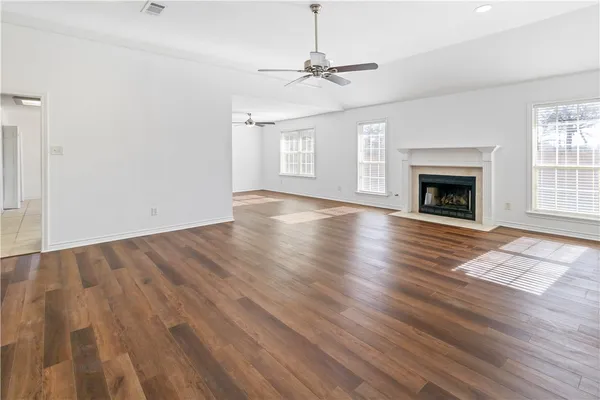 a view of an empty room with wooden floor fireplace and a window